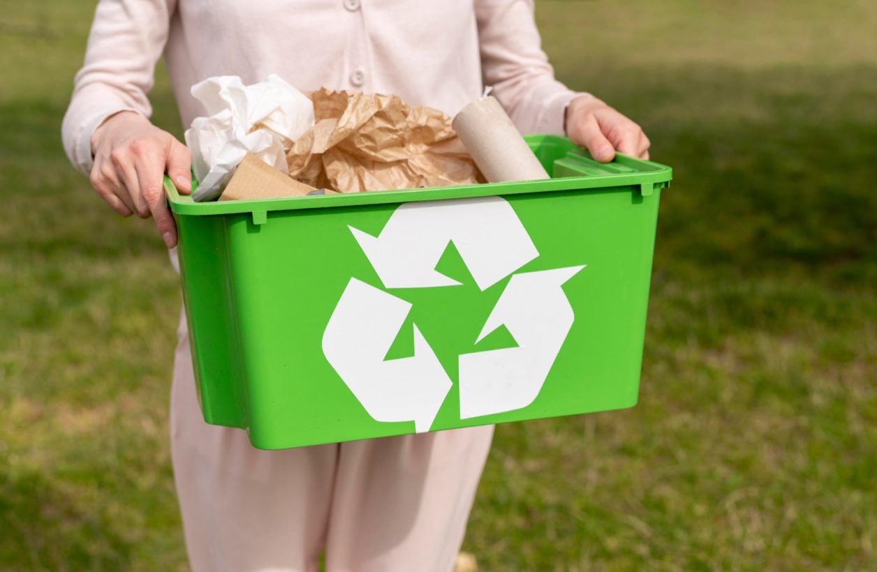 Pessoa carregando uma caixa verde de reciclagem